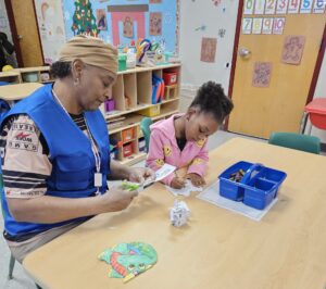 Older adult volunteer works with student in a classroom