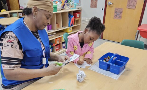 Older adult volunteer works with student in a classroom