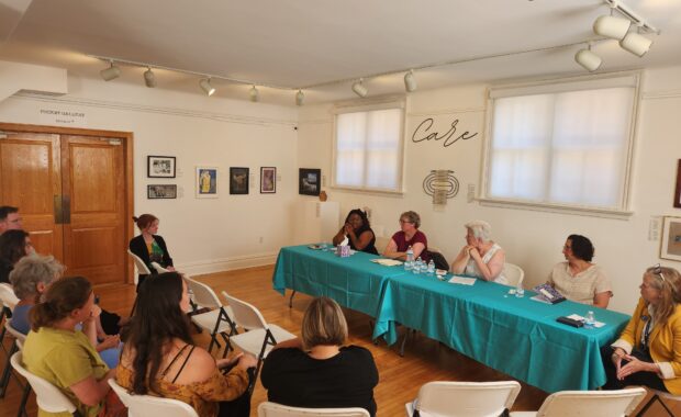 An audience engages with a panel of speakers in an art gallery
