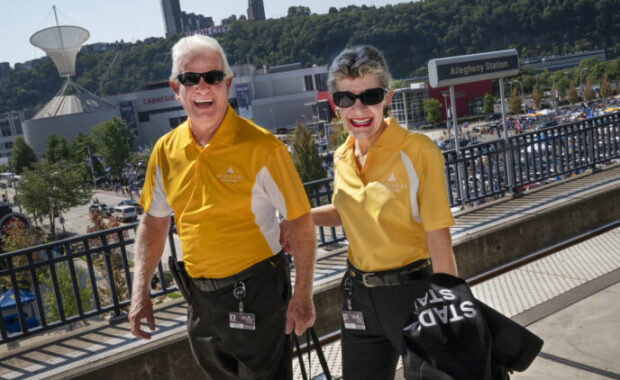 Couple in matching yellow shirts and sunglasses walking along path