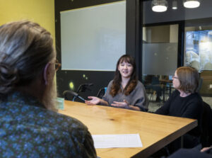 three women in office setting sitting around a table talking