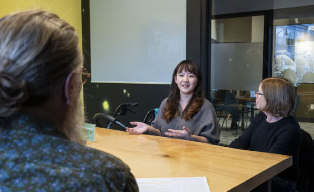 three women in office setting sitting around a table talking
