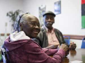 Black woman smiles at camera while holding playing cards