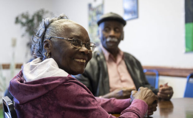 Black woman smiles at camera while holding playing cards