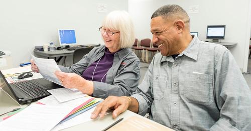 Woman reviews paperwork with a gentleman sat at desk