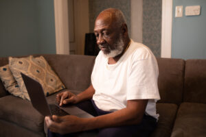man sitting on couch looking at computer