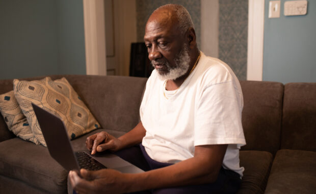 man sitting on couch looking at computer