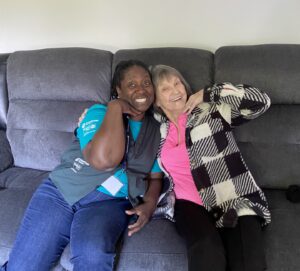 Senior Companion Marie poses with client on a couch