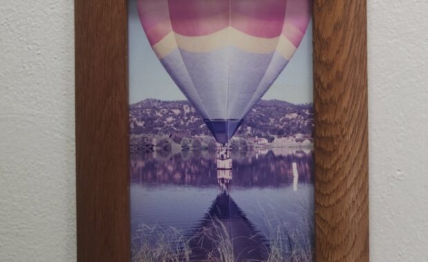 A hot air balloon floats over a body of water