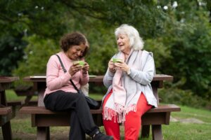 two women enjoy drinks outside on a bench