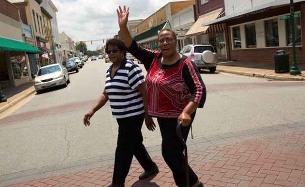 Two women crossing street- one waving