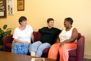 group of three women sitting on couch