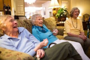 three women laugh together on couch