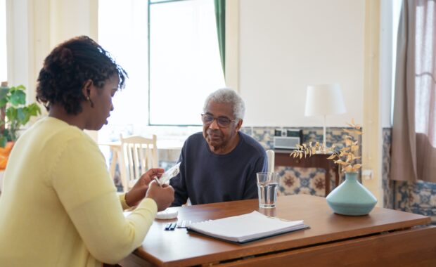 caregiver helps older gentleman with medicine