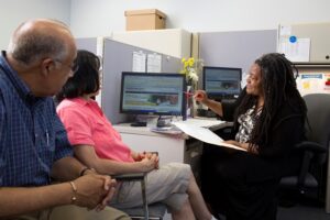 woman showing couple computer screen and paperwork