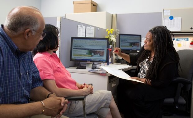 woman showing couple computer screen and paperwork