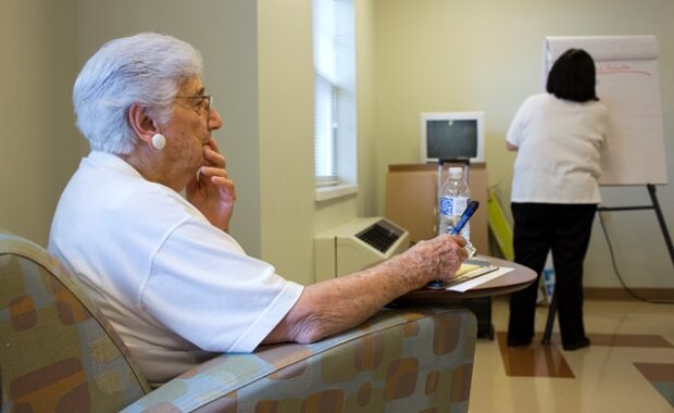 Woman sitting while thinking, holding a pen to a piece of paper